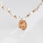 Elegant necklace featuring a string of pearls and rose gold beads, with a central rose gold pendant engraved with a detailed classical profile. Elegant pearl jewelry