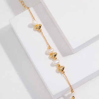 Elegant  chain bracelet adorned with natural beads and circular charms, displayed on a white rectangular stand. Elegant pearl jewelry