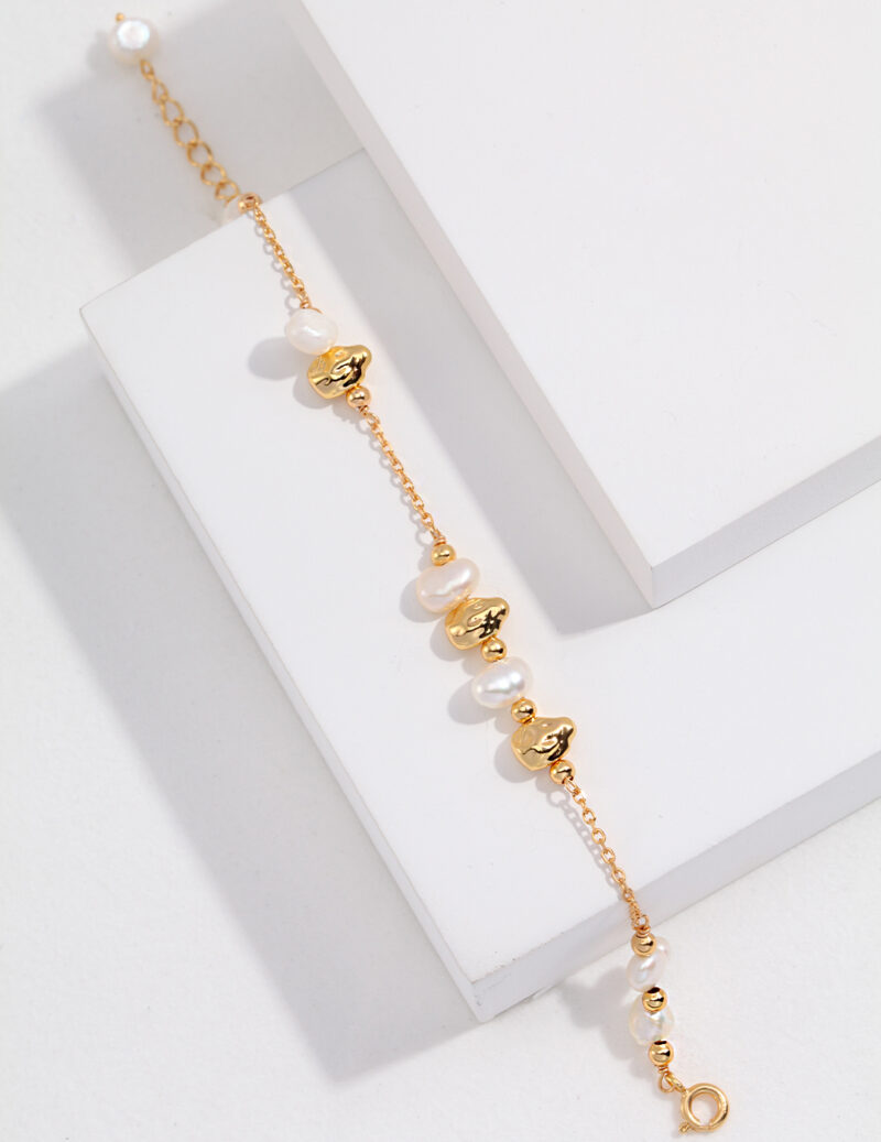 Elegant  chain bracelet adorned with natural beads and circular charms, displayed on a white rectangular stand. Elegant pearl jewelry