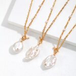 Three elegant necklaces with freshwater pearl accents hanging over the edge of a white display, each featuring a unique baroque pearl pendant, highlighted by soft, natural light. Elegant pearl jewelry