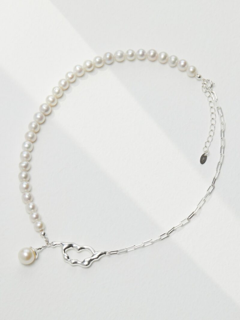 A necklace on a white background, featuring a sterling silver chain with a heart-shaped clasp and a single pearl pendant. Elegant pearl jewelry