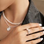 Close-up image of a woman's neck adorned with a freshwater pearl necklace and a pendant. Elegant pearl jewelry