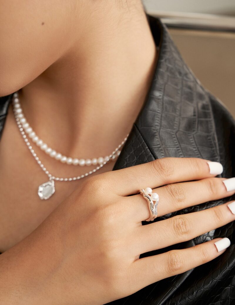 Close-up image of a woman's neck adorned with a freshwater pearl necklace and a pendant. Elegant pearl jewelry