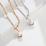 Two elegant necklaces, one  pearl jewelry and one gold pearl jewelry, draped over a white platform in bright sunlight, creating sharp shadows. Elegant pearl jewelry