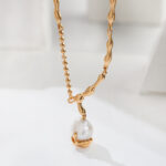 A chain necklace with an irregular link design and a single large natural pearl pendant, displayed against a softly lit white background. Elegant pearl jewelry