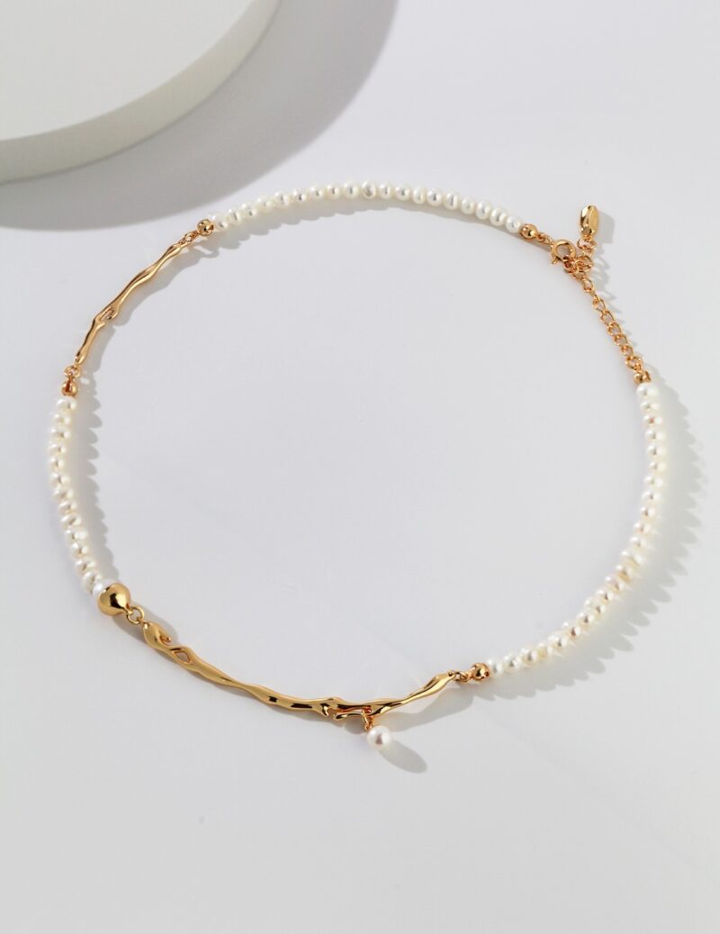 A necklace with a central gold twisted segment, featuring a gold clasp and adjustable chain, displayed against a white background with a subtle shadow. Elegant pearl jewelry