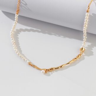 An elegant necklace with a gold chain detail, displayed on a white surface with soft shadows. Elegant pearl jewelry