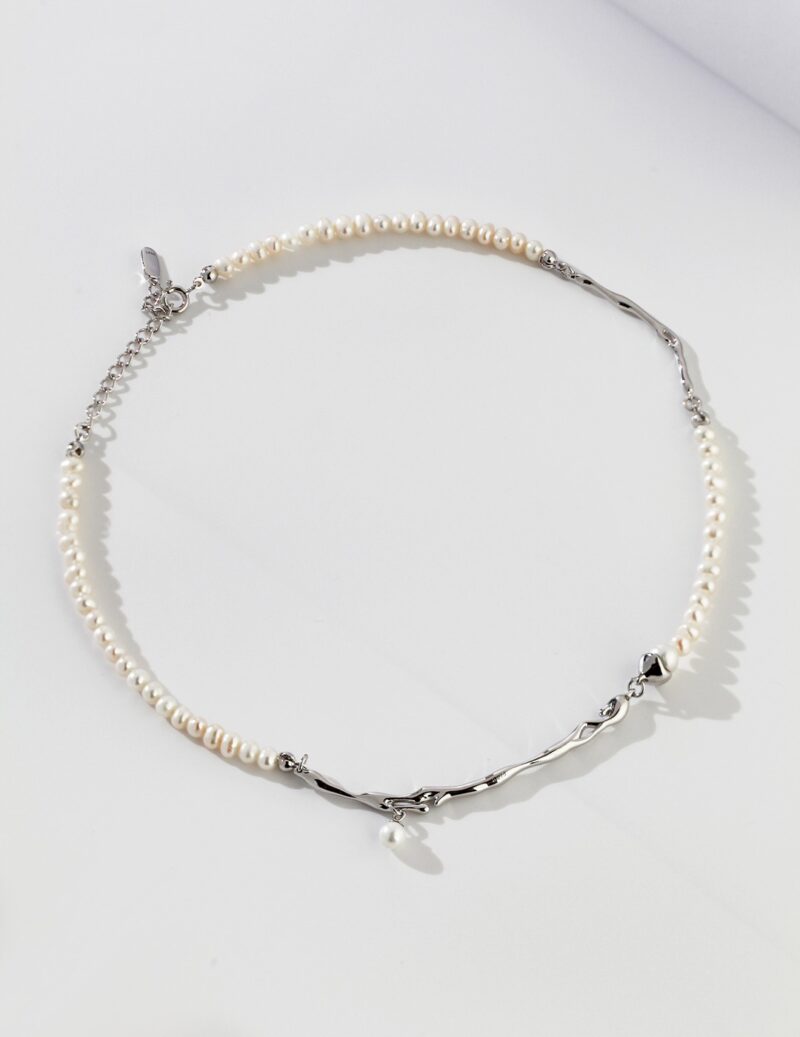 A delicatebracelet made of alternating sections of freshwater pearls and silver chain links, displayed on a white background with soft shadows. Elegant pearl jewelry