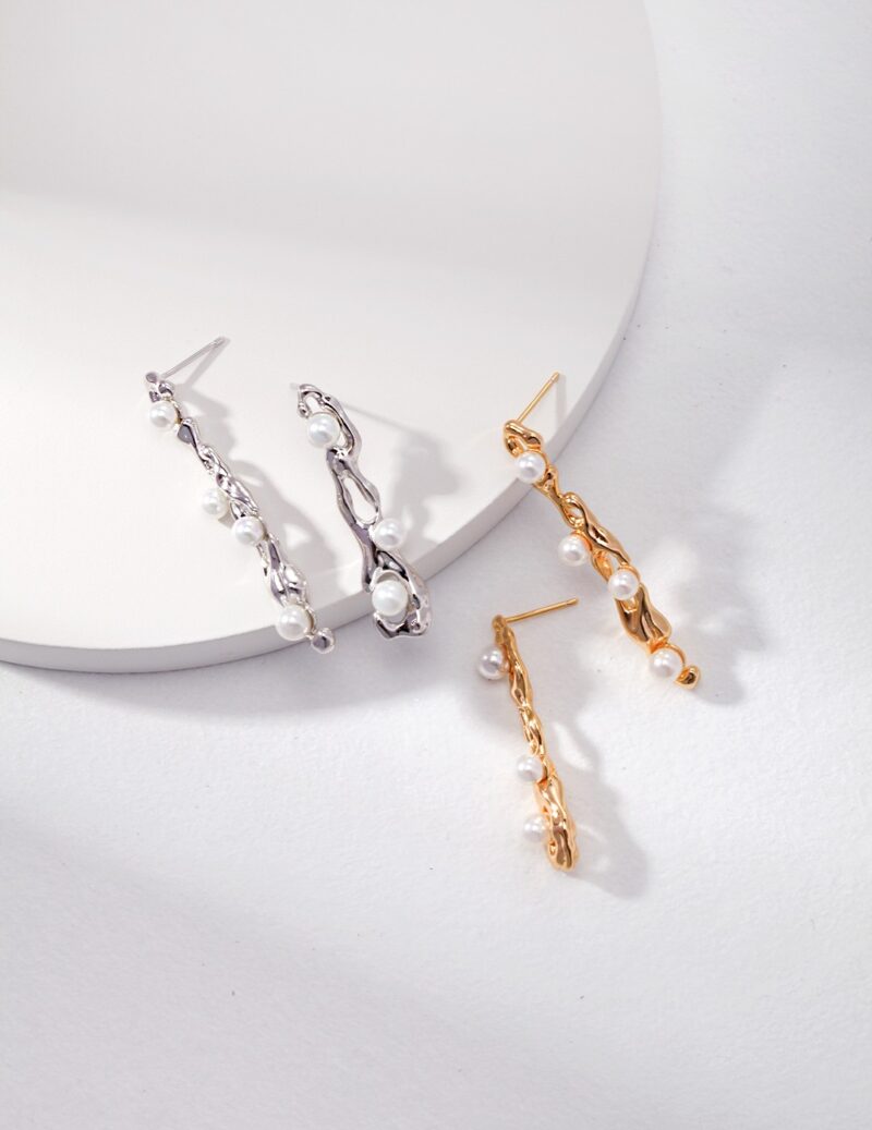 Two pairs of elegant earrings displayed on a white surface; one pair is with a twisted design and natural pearl embellishments, the other is gold with a similar twisted style and freshwater pearl accents Elegant pearl jewelry