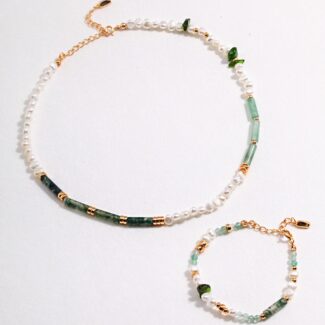 A photo of a jewelry set featuring natural pearls, green gemstones, and gold accents laid out on a white background. Elegant pearl jewelry