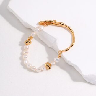 A gold hoop earring adorned with and tiny gold charms, elegantly placed on a white textured surface. Elegant pearl jewelry