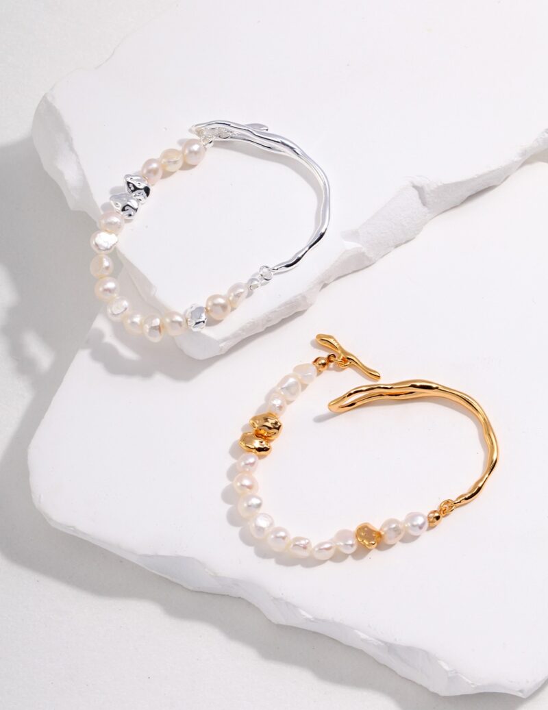 Sentence with Product Name: Two bracelets displayed on a jagged white rock surface. The top bracelet has silver accents, while the lower one features gold pearl jewelry. Elegant pearl jewelry