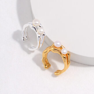 Two elegant  rings displayed on a light background, one sterling jewelry and one gold jewelry, with unique, wavy band designs. Elegant pearl jewelry