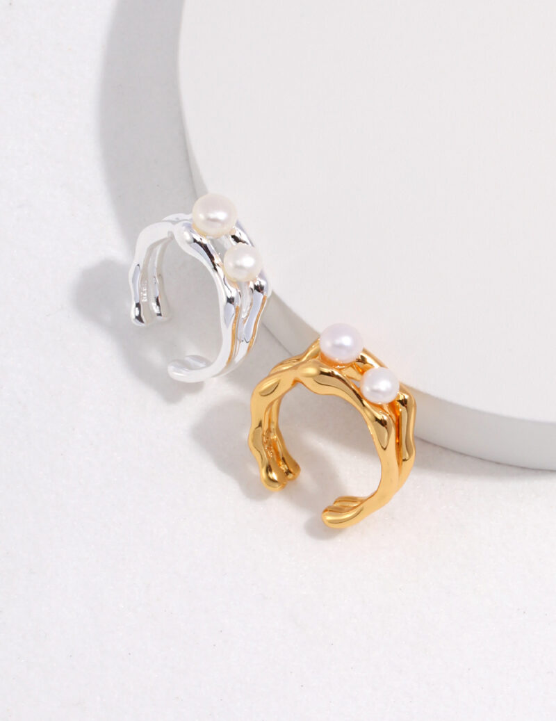 Two elegant  rings displayed on a light background, one sterling jewelry and one gold jewelry, with unique, wavy band designs. Elegant pearl jewelry