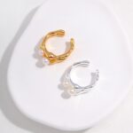 Two  rings, one gold and one silver, displayed on a white, oval-shaped surface. Elegant pearl jewelry