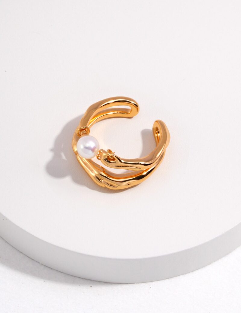 A open-ended ring with a natural pearl accent, elegantly displayed on a white cylindrical stand against a light background. The ring has a textured, wavy design, enhancing its luxurious Elegant pearl jewelry