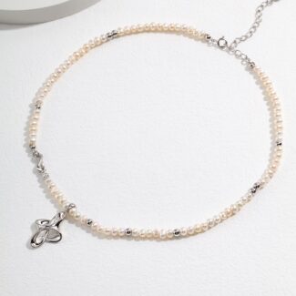 An elegant  necklace with a sterling silver clasp, displayed on a light gray surface, showcasing its delicate beauty and sophisticated design. Elegant pearl jewelry