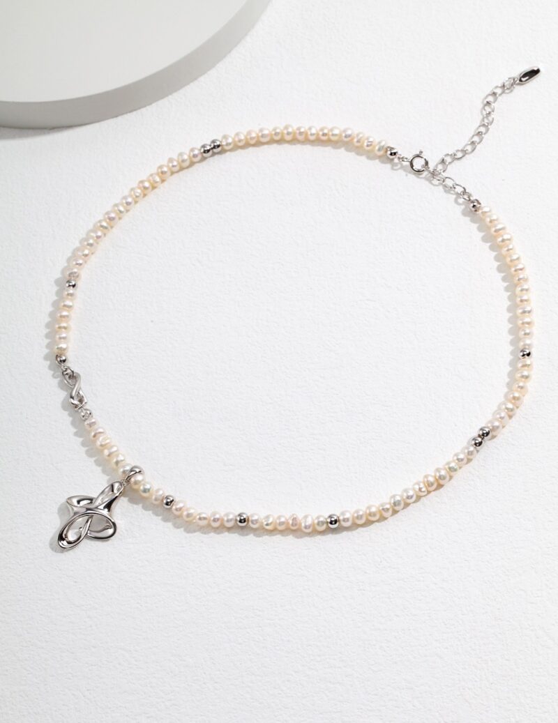 An elegant  necklace with a sterling silver clasp, displayed on a light gray surface, showcasing its delicate beauty and sophisticated design. Elegant pearl jewelry