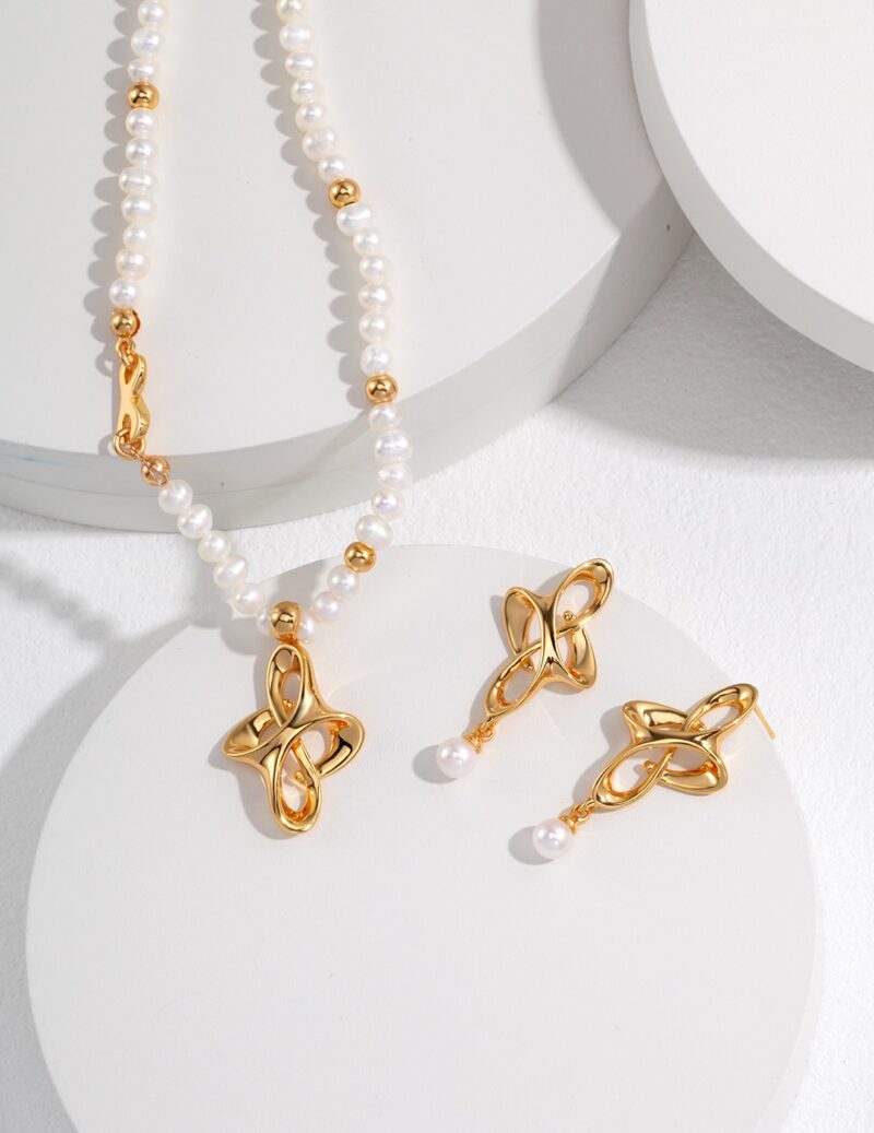 The product named o_1gh7t4hqa1d31dq31g1vkpe1nh2u is displayed on a white, circular surface, featuring a jewelry set that includes a pearl necklace with 18k Gold Vermeil accents and matching gold earrings adorned with floral designs and pearl drops. Elegant pearl jewelry