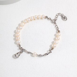 A bracelet with alternating segments of smooth natural pearls and a sterling silver chain, featuring a silver charm and clasp, displayed on a white textured surface. Elegant pearl jewelry