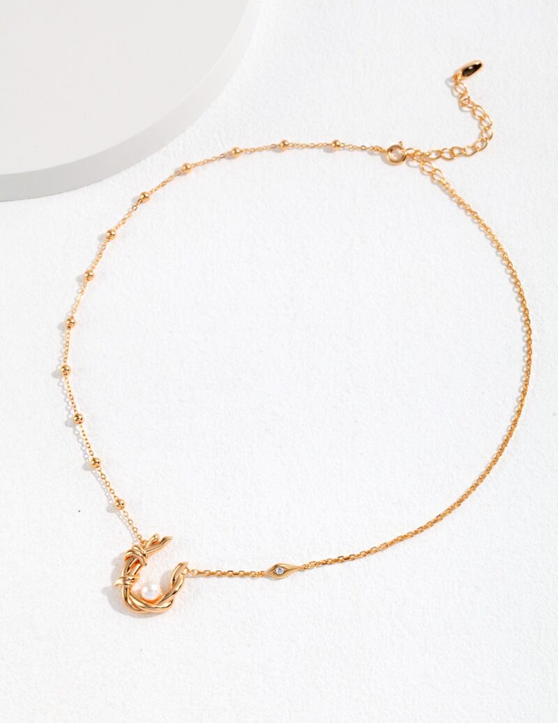 Gold pearl jewelry bracelet featuring a delicate chain with a crescent moon and star charm, displayed on a light textured surface.