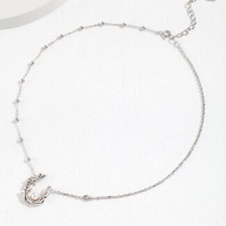 Silver ankle bracelet featuring a charm and freshwater pearl accents, displayed on a white surface with soft shadows. Elegant pearl jewelry.