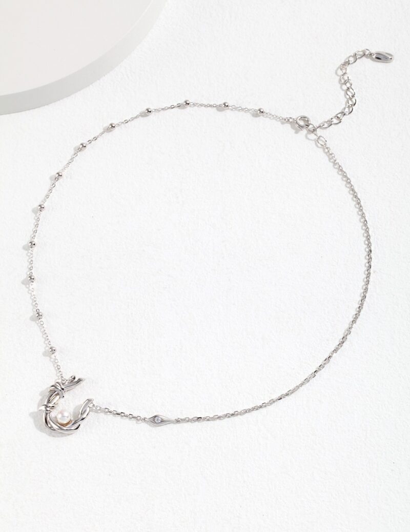 Silver ankle bracelet featuring a charm and freshwater pearl accents, displayed on a white surface with soft shadows. Elegant pearl jewelry.