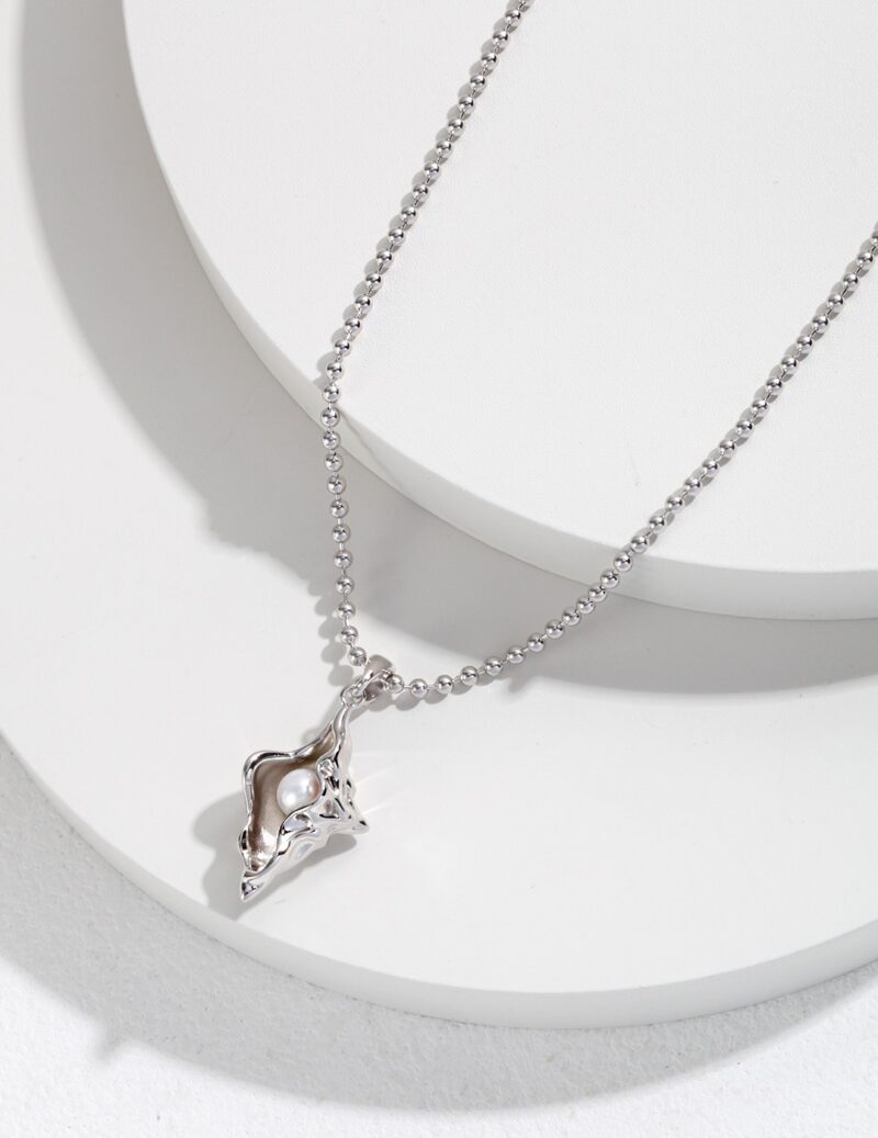 A silver necklace with a fox pendant displayed on a white stand, featuring sterling pearl jewelry and a pearl at the pendant's center. Elegant pearl jewelry