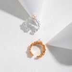 Two elegant  rings, one silver and one gold pearl jewelry, displayed on a white surface intersected by soft geometric shadows, creating a minimalist and refined presentation. Elegant pearl jewelry