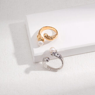 Two elegant rings displayed on a white surface; one with a natural pearl accent and a wing design, and the other with a circular clear gemstone. Elegant pearl jewelry