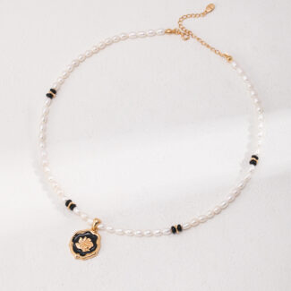 A natural pearl bracelet with gold details and a pendant featuring a flower design, displayed against a textured white background. Elegant pearl jewelry