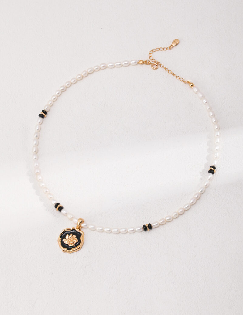 A natural pearl bracelet with gold details and a pendant featuring a flower design, displayed against a textured white background. Elegant pearl jewelry