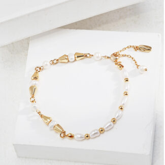 An elegant bracelet with gold accents displayed on a white surface. The bracelet features a mix of large and small pearls interspersed with shiny gold beads and clasps. Elegant pearl jewelry