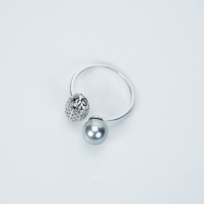 A ring with a lustrous freshwater pearl and a decorative silver filigree charm, displayed against a plain white background. Elegant pearl jewelry