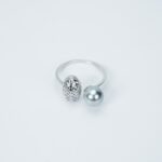 A ring with a simple silver band featuring one textured silver bead and one smooth light blue set against a plain white background.