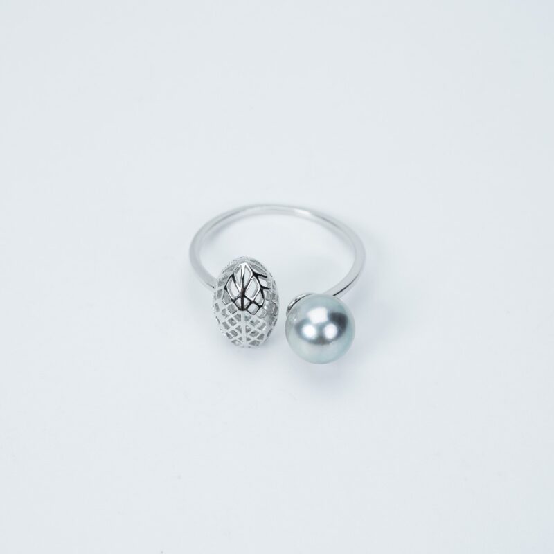 A ring with a simple silver band featuring one textured silver bead and one smooth light blue set against a plain white background.