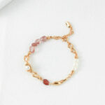 An elegant bracelet featuring a combination of pink gemstones and freshwater pearls set in delicate gold chain links, displayed on a white textured background. Elegant pearl jewelry