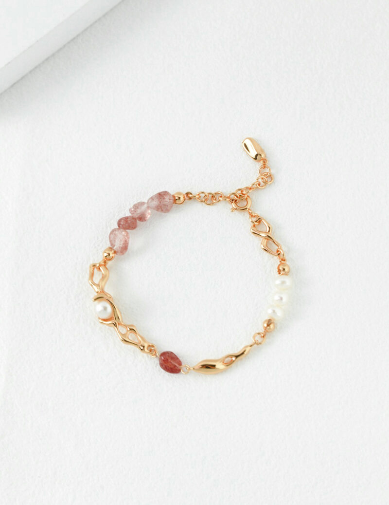 An elegant bracelet featuring a combination of pink gemstones and freshwater pearls set in delicate gold chain links, displayed on a white textured background. Elegant pearl jewelry