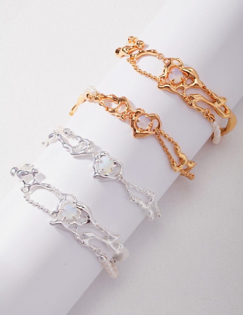 Three delicate bracelets displayed on a cylindrical white holder, featuring intricate link designs in gold pearl jewelry and sterling pearl jewelry colors. Elegant pearl jewelry