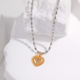 A silver chain necklace with pendant laying on a textured white surface. Elegant pearl jewelry