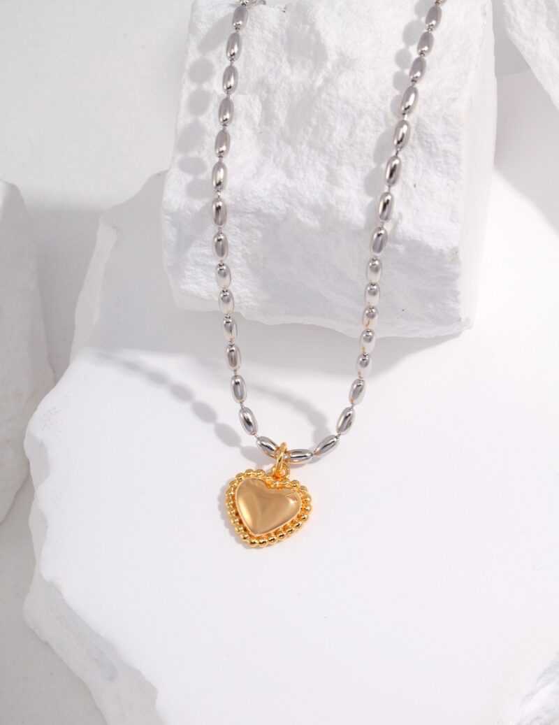 A silver chain necklace with pendant laying on a textured white surface. Elegant pearl jewelry