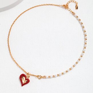 Gold chain bracelet featuring pearls and a red heart-shaped charm, displayed on a white surface with soft shadows. Elegant pearl jewelry