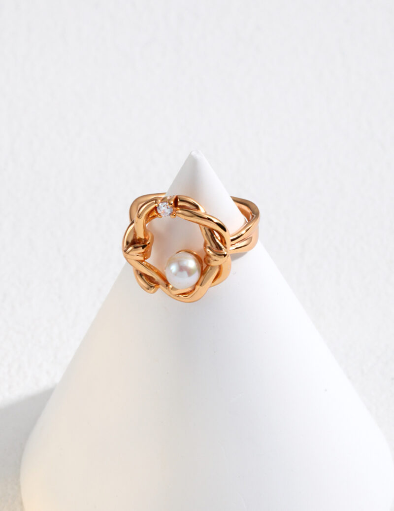 An elegant  ring with a pearl, displayed on a white cone-shaped stand against a light gray background. Elegant pearl jewelry