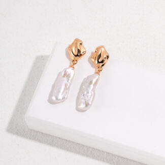 A pair of elegant earrings with rose gold metal clasps and natural pearl pendants, displayed on a white surface. Elegant pearl jewelry