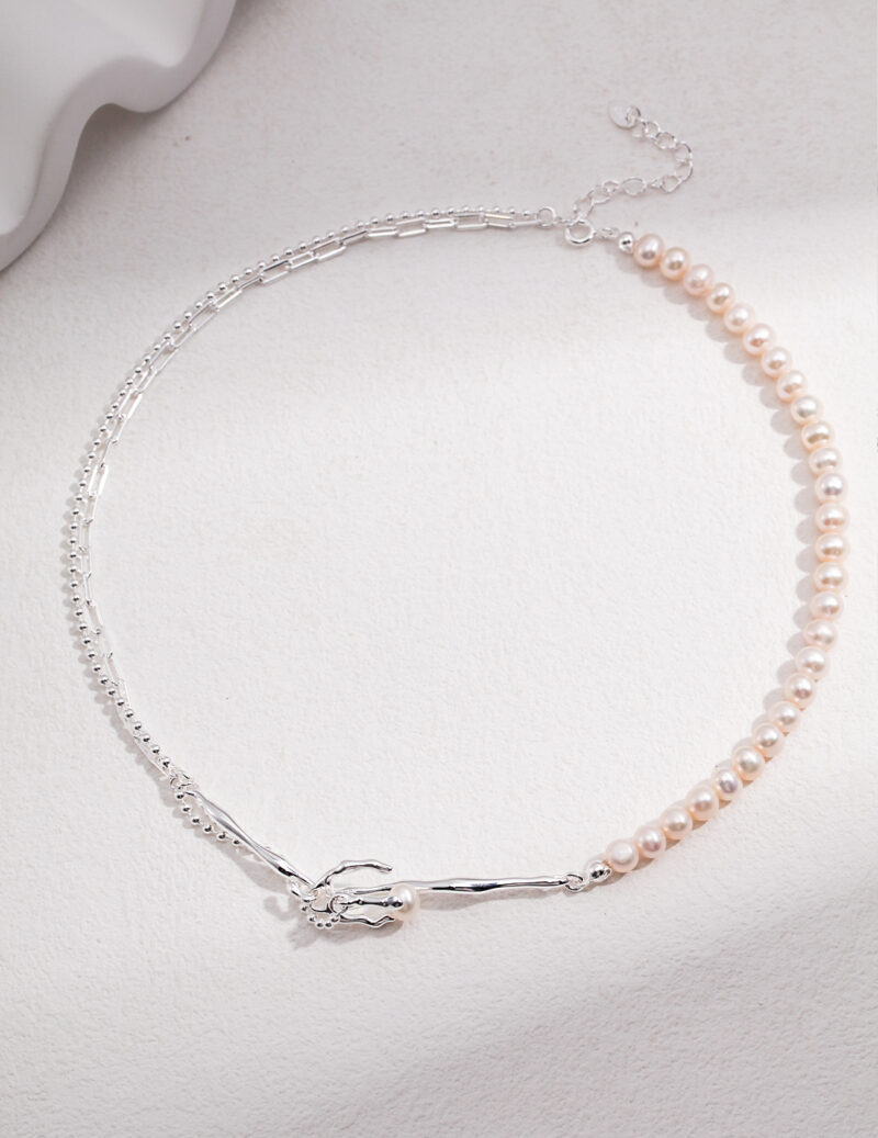 A delicate necklace featuring a half-string of lustrous freshwater pearls and a half-string of sterling silver chain, with a small silver clasp on a white textured background. Elegant pearl jewelry