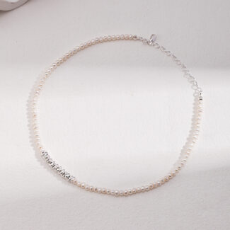 A necklace with a silver chain and clasp, lying on a white surface with soft lighting. The central decorative feature spells "soul mate" in cursive silver letters. Elegant pearl jewelry