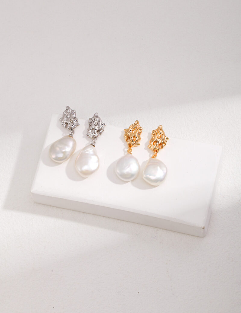 Three pairs of pearl earrings displayed on a white stand, featuring sterling pearl jewelry and gold pearl jewelry designs with large pearl drops, on a textured light background. Elegant pearl jewelry