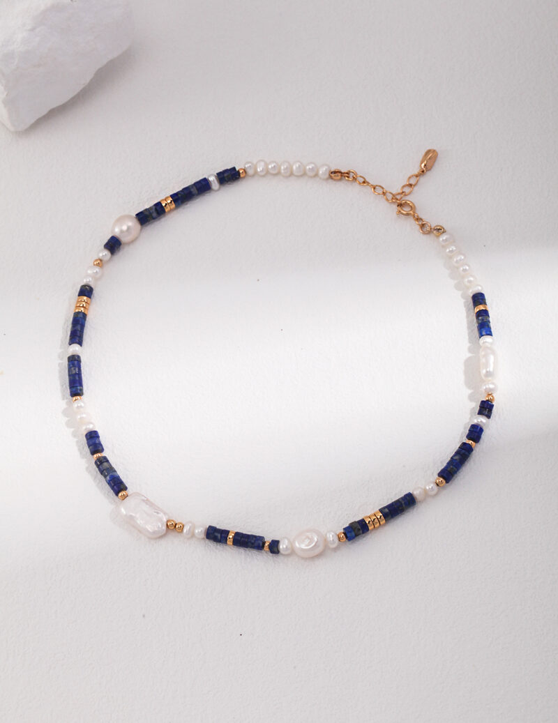 An elegant bracelet featuring a pattern of deep blue rectangular gemstones, natural pearls, and small gold-tone accents laid out on a light surface. Elegant pearl jewelry