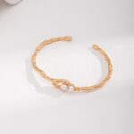 Golden bracelet with a twisted texture and a freshwater pearl set at the center, displayed on a white background. Elegant pearl jewelry