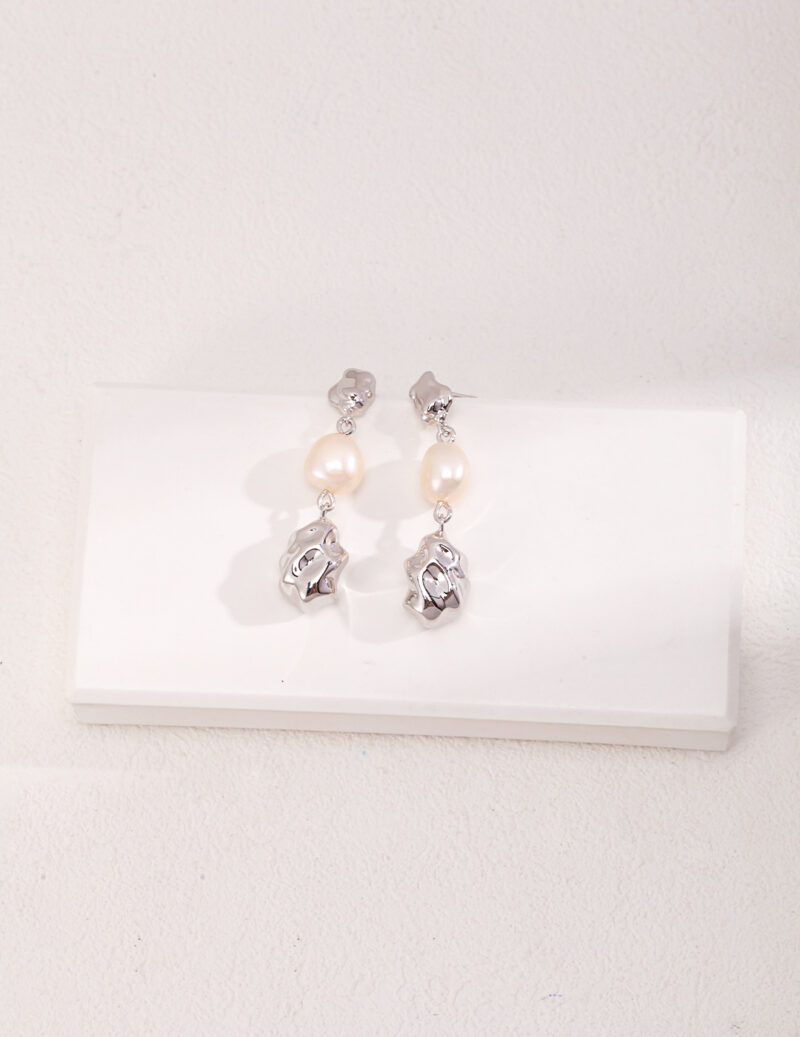 A pair of elegant drop o_1hd84fjsl1ug11s811ifm1lgb22m7 displayed on a white background. Each earring features a small gold vermeil rose design at the top, followed by a round pearl, and another gold vermeil rose at the bottom. The earrings have a polished finish, enhancing their sophisticated allure. Elegant pearl jewelry